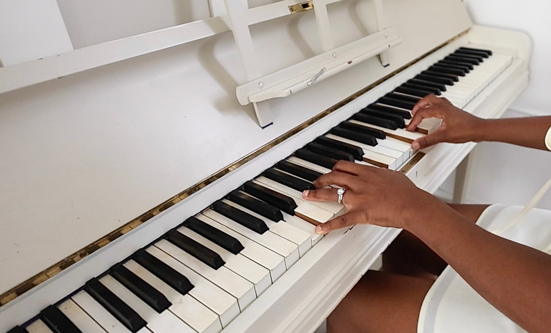 Hands playing the white piano at Root and Bloom